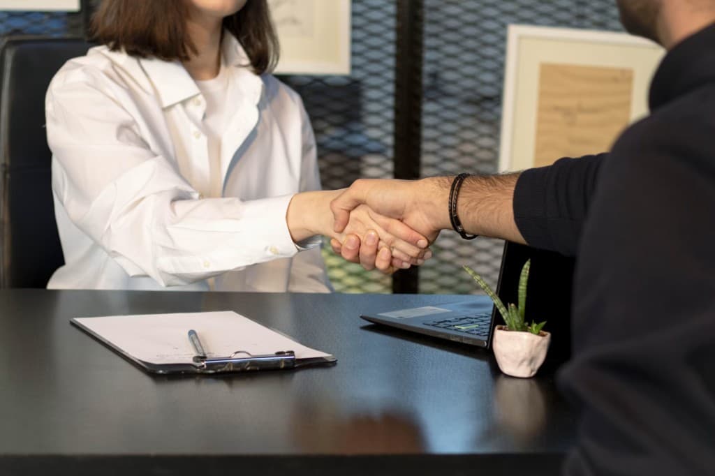 Employer and candidate shaking hands to confirm a hiring agreement in a professional office